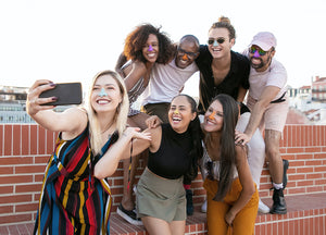 Diverse group of men and women posing for a selfie, each wearing colorful zinc oxide sunscreen on their noses and smiling